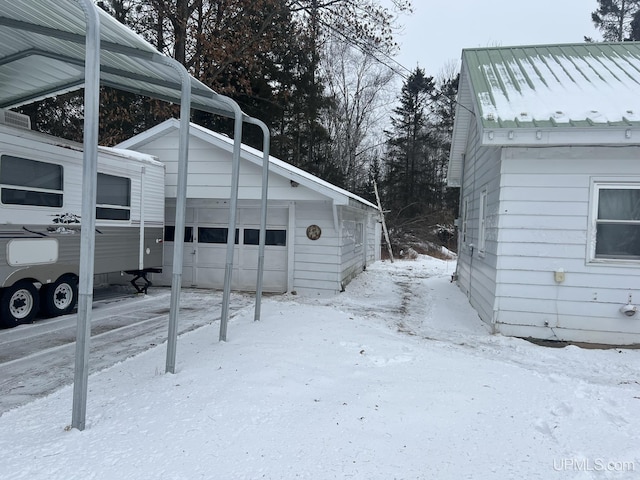 view of snowy exterior with a garage and an outdoor structure