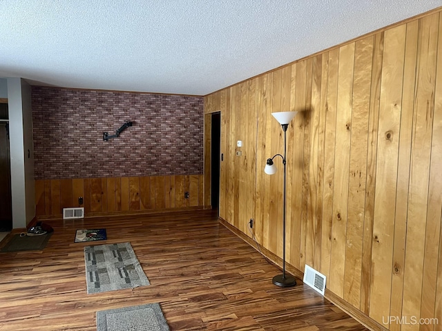 unfurnished room with dark hardwood / wood-style flooring, a textured ceiling, and wood walls