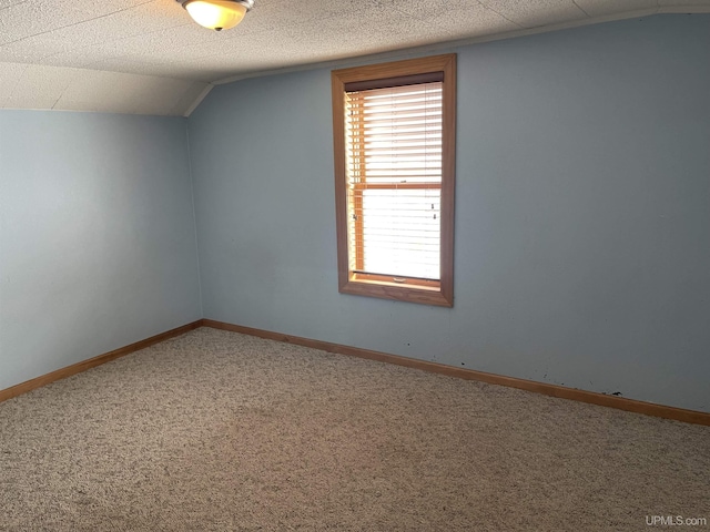 spare room featuring lofted ceiling, a textured ceiling, and carpet