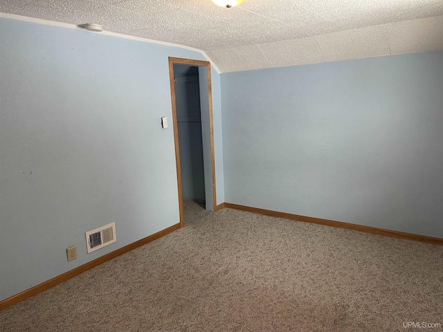 carpeted empty room with lofted ceiling and a textured ceiling