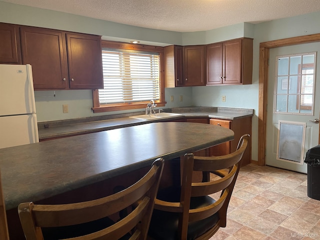 kitchen with white fridge, sink, and a textured ceiling