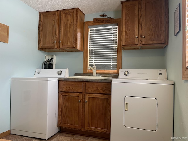 laundry room with sink, washing machine and dryer, cabinets, and a textured ceiling