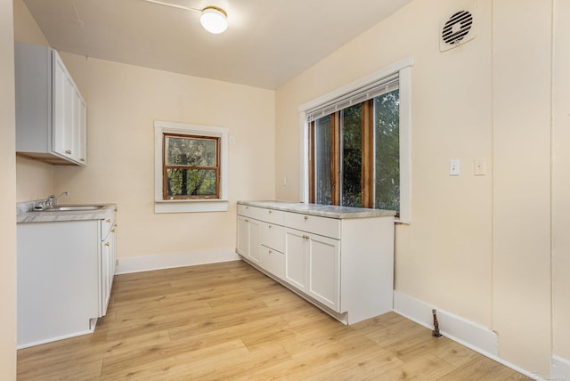 kitchen with white cabinetry, sink, and light hardwood / wood-style flooring