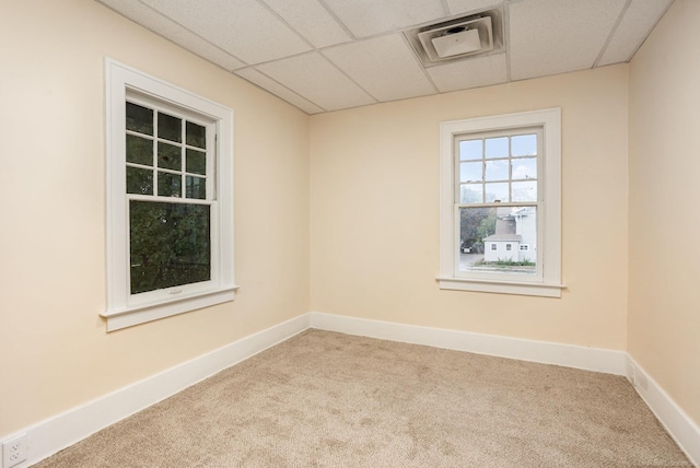 empty room featuring light carpet and a drop ceiling