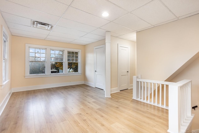 spare room featuring a paneled ceiling and light wood-type flooring