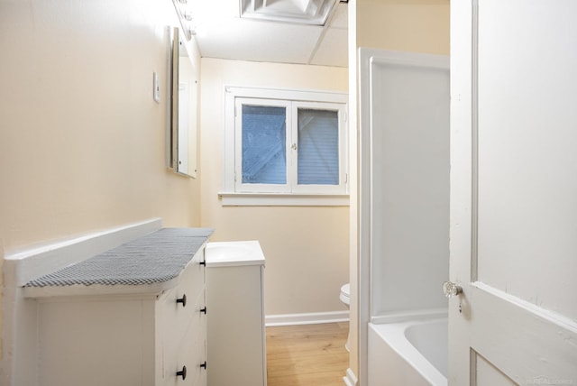 bathroom with vanity, hardwood / wood-style flooring, a tub, and toilet