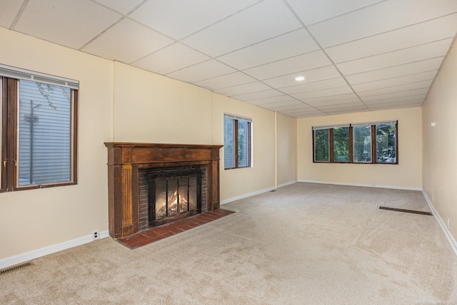 unfurnished living room featuring a paneled ceiling, a healthy amount of sunlight, and carpet