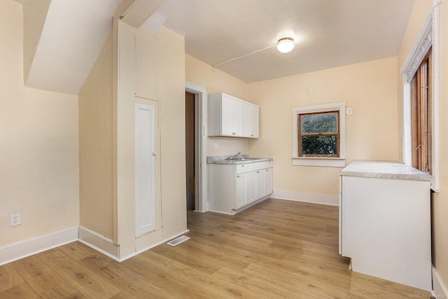 clothes washing area with sink and light hardwood / wood-style floors