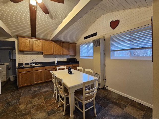 kitchen with tasteful backsplash, lofted ceiling with beams, sink, a kitchen bar, and a center island