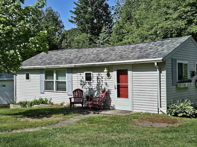 rear view of property featuring a garage and a lawn