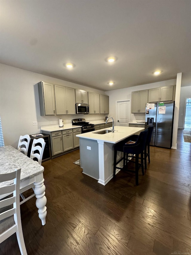 kitchen featuring gray cabinetry, sink, stainless steel appliances, and an island with sink