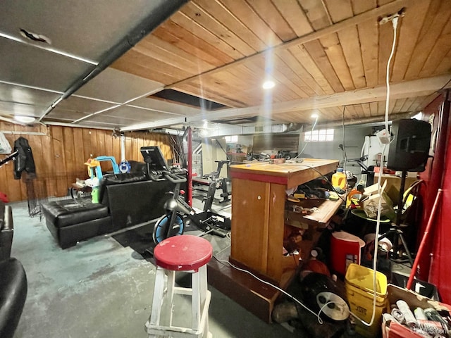 basement featuring wooden ceiling, a workshop area, and wood walls