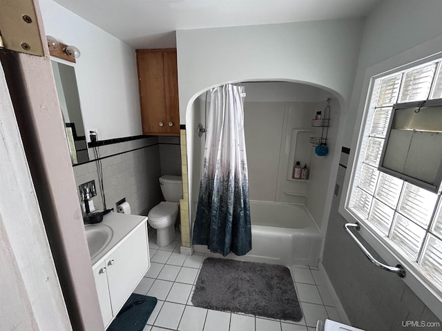 full bathroom featuring shower / bathtub combination with curtain, tile walls, vanity, tile patterned floors, and toilet