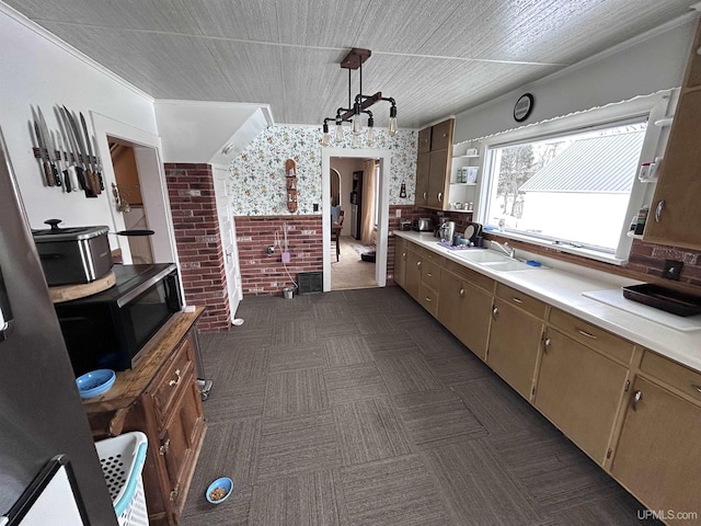 kitchen featuring lofted ceiling, sink, dark carpet, brick wall, and decorative light fixtures