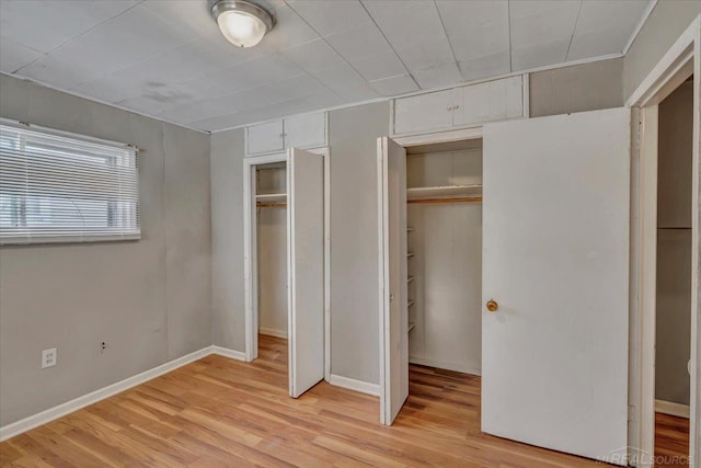 unfurnished bedroom with two closets and light hardwood / wood-style floors