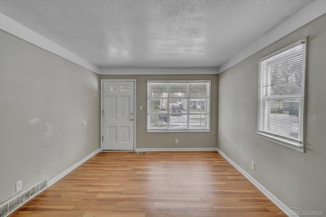 unfurnished room featuring light hardwood / wood-style flooring and a textured ceiling