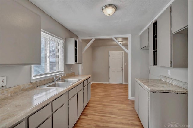 kitchen with sink, gray cabinetry, a textured ceiling, and light hardwood / wood-style flooring