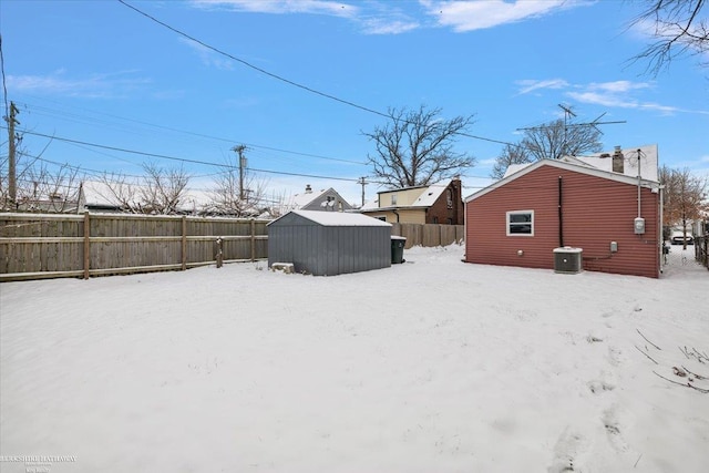 yard covered in snow featuring a storage shed and central AC