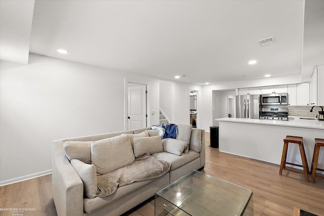 living room with sink and light hardwood / wood-style flooring