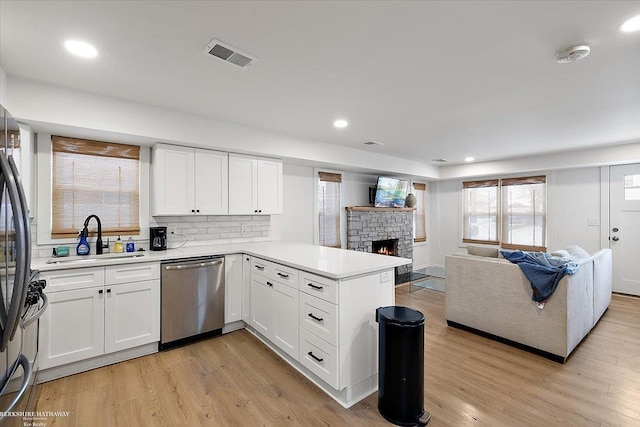 kitchen featuring sink, appliances with stainless steel finishes, white cabinetry, light hardwood / wood-style floors, and kitchen peninsula