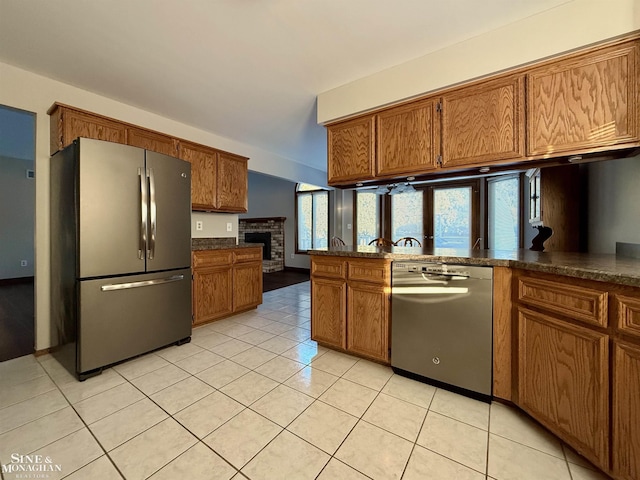 kitchen with appliances with stainless steel finishes, kitchen peninsula, and light tile patterned floors