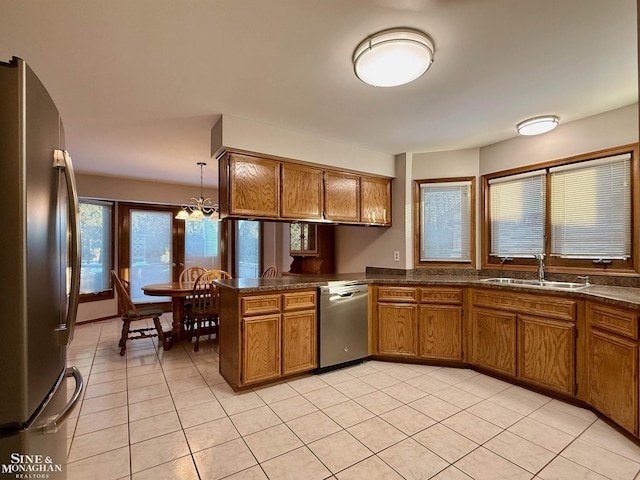 kitchen featuring sink, decorative light fixtures, light tile patterned floors, appliances with stainless steel finishes, and kitchen peninsula