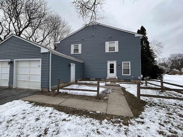 snow covered rear of property with a garage