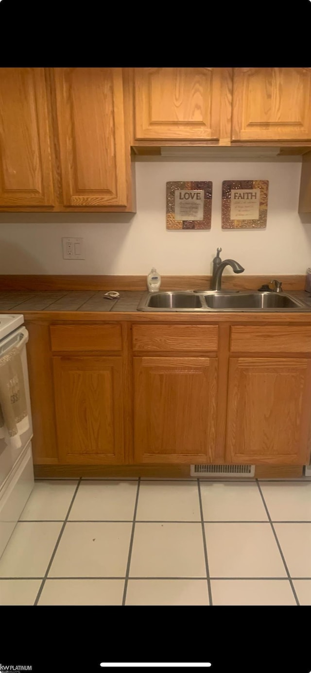 kitchen with sink, range, and light tile patterned floors