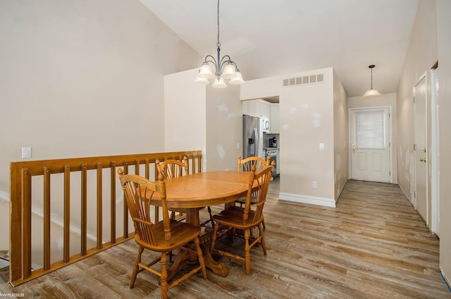 dining space featuring vaulted ceiling, visible vents, baseboards, light wood-type flooring, and a notable chandelier