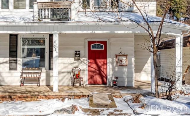 snow covered property entrance featuring covered porch