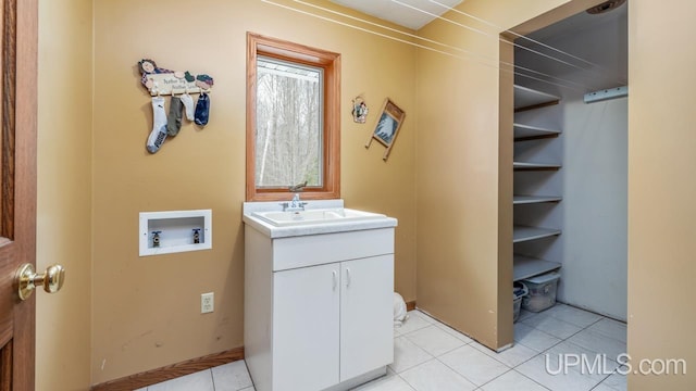 washroom with hookup for a washing machine, sink, light tile patterned floors, and cabinets