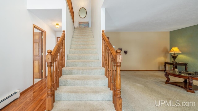 stairway with a baseboard radiator and carpet