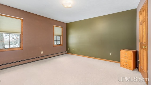 carpeted spare room featuring a baseboard radiator and plenty of natural light