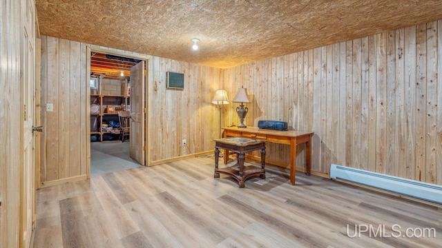 office area with a baseboard heating unit, wood-type flooring, and wood walls