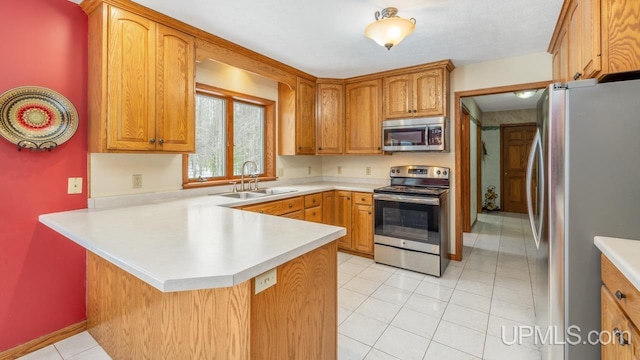 kitchen featuring stainless steel appliances, sink, light tile patterned floors, and kitchen peninsula