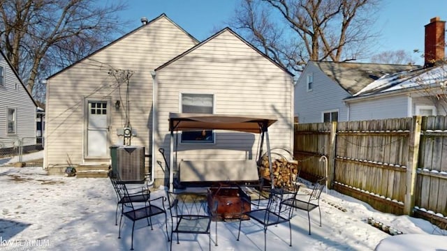 snow covered back of property with central AC unit