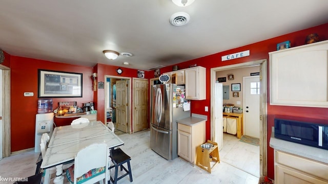 kitchen with stainless steel fridge, light wood-type flooring, and white cabinets