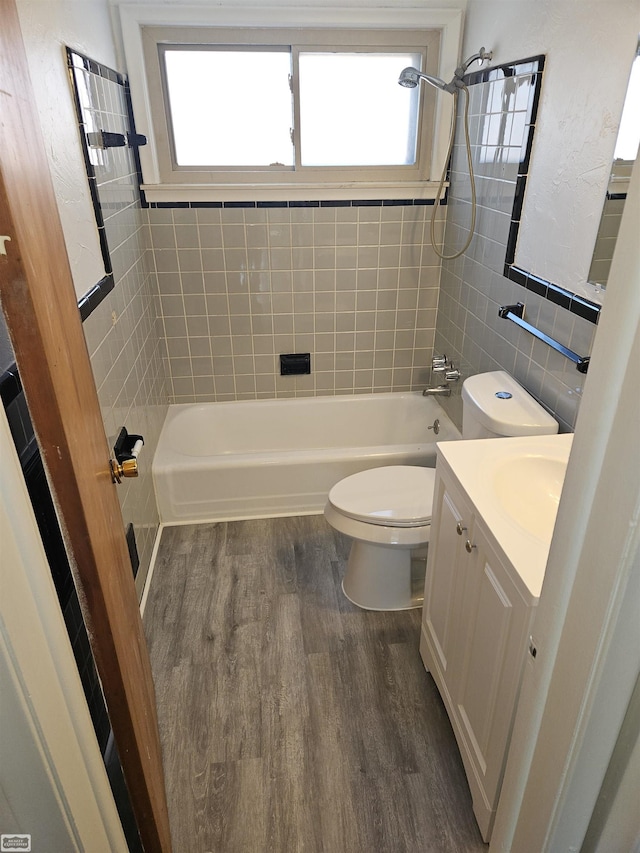 full bathroom with tile walls, hardwood / wood-style flooring, a wealth of natural light, and tiled shower / bath combo