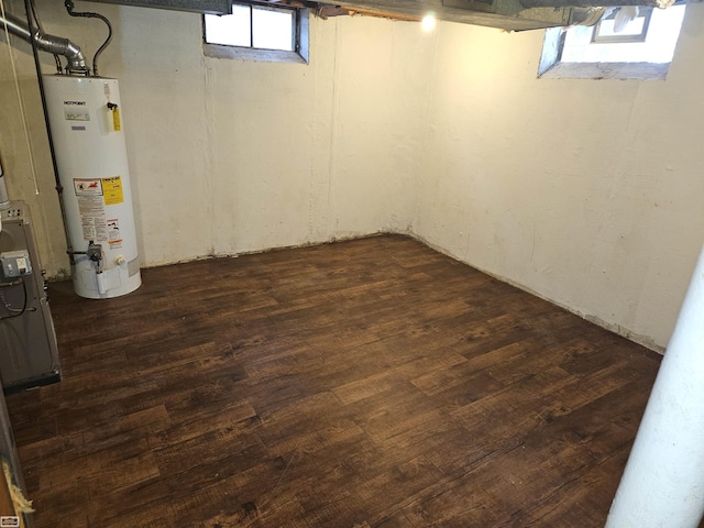 basement featuring dark hardwood / wood-style floors and water heater