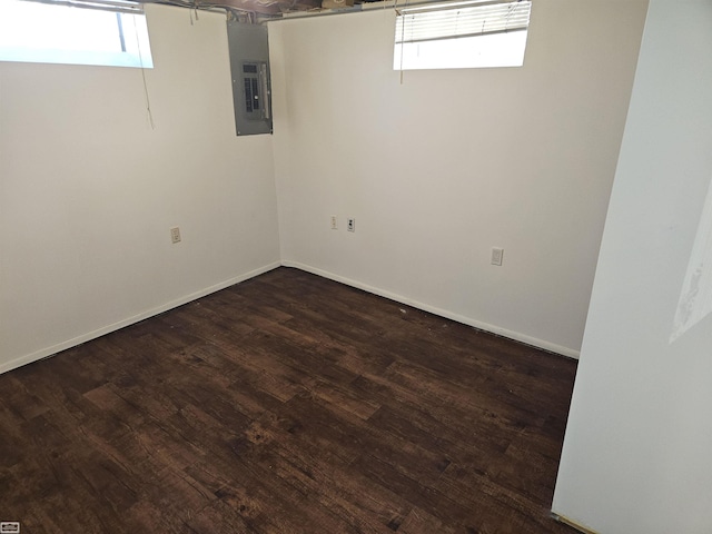 basement with dark hardwood / wood-style flooring, electric panel, and a healthy amount of sunlight