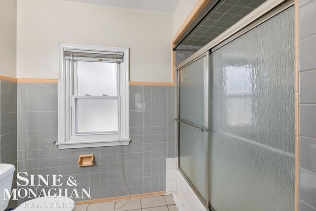 bathroom with enclosed tub / shower combo, tile walls, tile patterned floors, and toilet