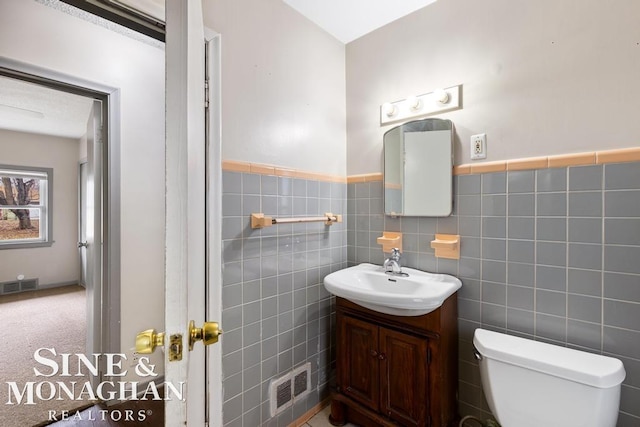 bathroom featuring tile walls, vanity, and toilet