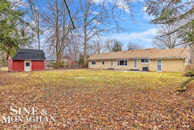 back of property with central AC, a storage shed, and a lawn