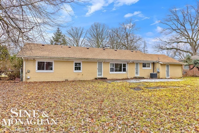 back of property with central AC unit and a lawn