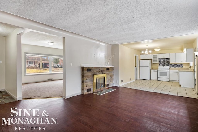 unfurnished living room featuring a textured ceiling, a fireplace, light hardwood / wood-style floors, and a chandelier