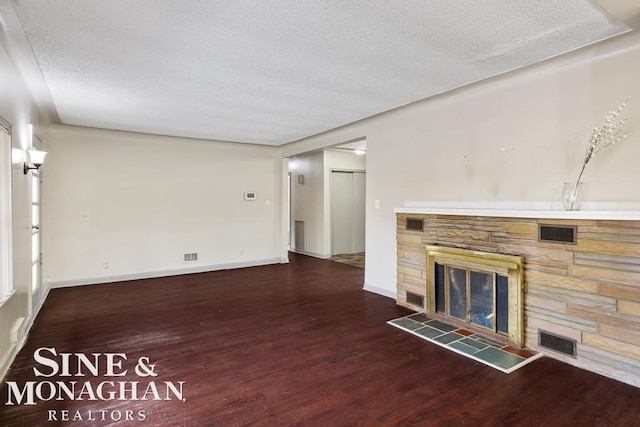 unfurnished living room with a fireplace, dark hardwood / wood-style floors, and a textured ceiling