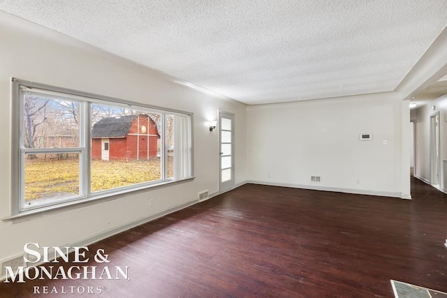 spare room featuring dark wood-type flooring and a textured ceiling