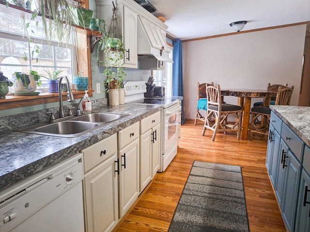 kitchen featuring sink, white appliances, ornamental molding, light hardwood / wood-style floors, and white cabinets