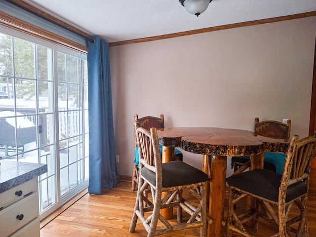 dining space with light hardwood / wood-style flooring and ornamental molding