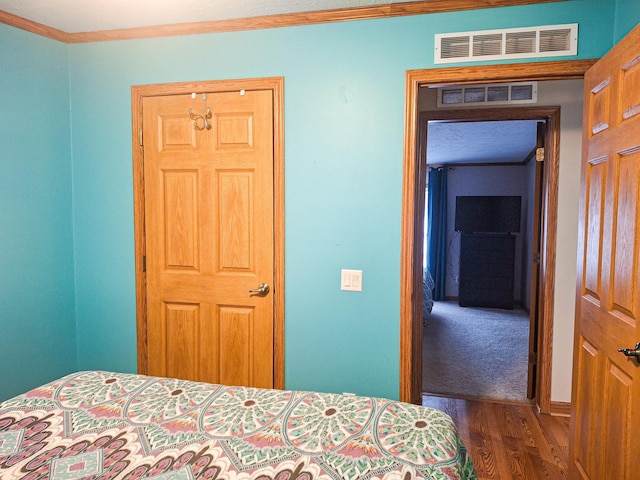 bedroom with crown molding and dark hardwood / wood-style floors